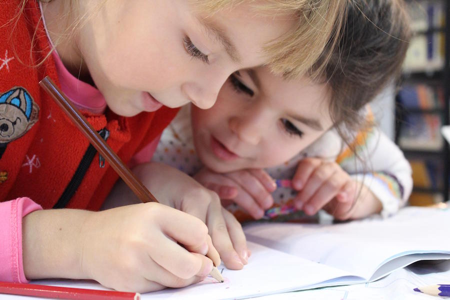 A photo of two children working together on homework -- teamwork