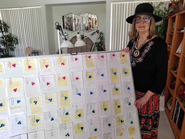 Author Joan K. Lacy standing next to her storyboard for her latest book in the Alex Cort Adventure Series